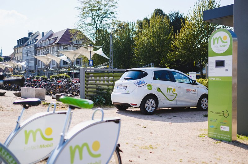 An einer Mobilitätsstation in Offenburg stehen Leihfahrräder und Carsharing-Fahrzeuge im weiß-grünen Design der Marke EinfachMobil.