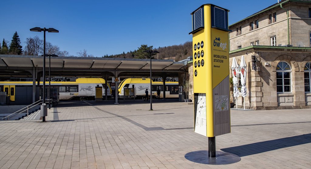 Eine gelbe Mobilitätssäule, die als Wegweiser zu nachhaltigen Verkehrsmitteln dient, steht am Bahnhof in Schwäbisch Gmünd.