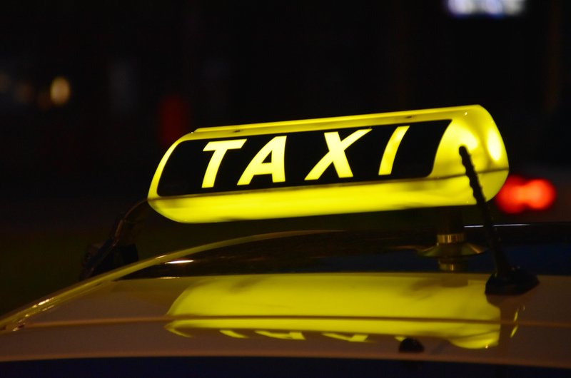 Ein leuchtendes Schild mit der Aufschrift Taxi ist auf dem Dach eines Autos angebracht.