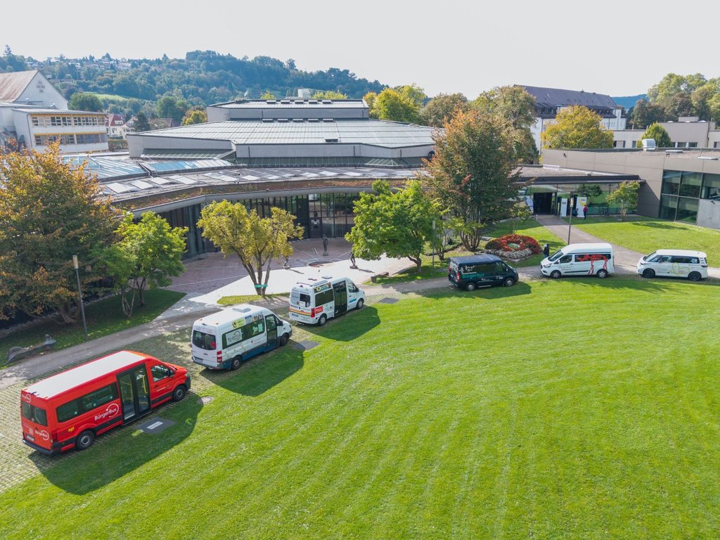 Mehrere Bürgerbusse stehen vor dem Kongresszentrum in Schwäbisch Gmünd auf der Wiese.