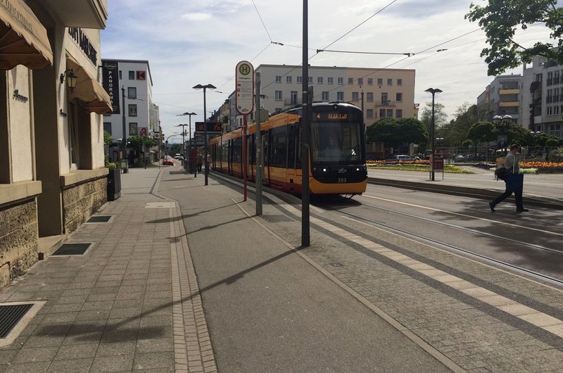 Eine gelb-rot-schwarze Straßenbahn fährt durch eine Straße in Karlsruhe.