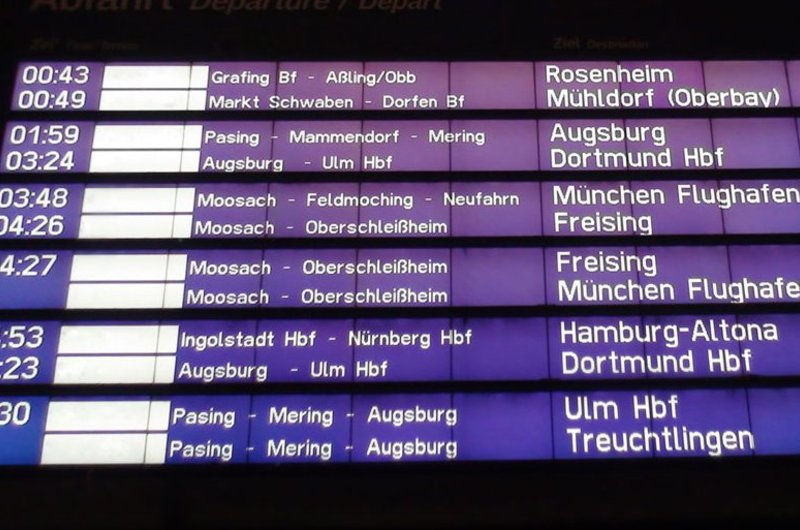 Eine digitale Anzeige zeigt mit weißer Schrift auf dunkelblauem Untergrund die Abfahrtzeiten von Bahnen an.