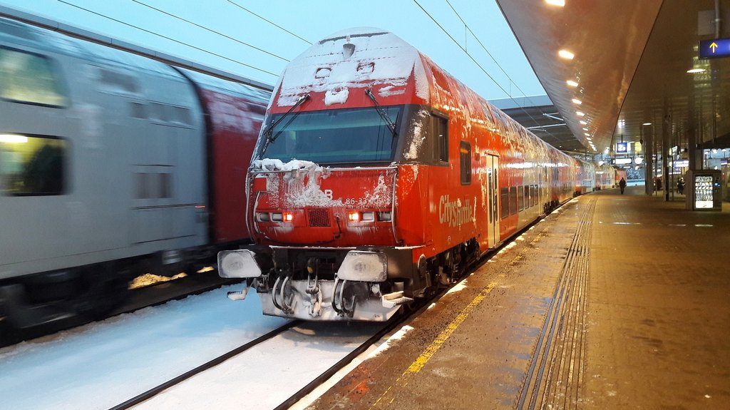 Ein schneebedeckter Zug steht in einem Bahnhof.