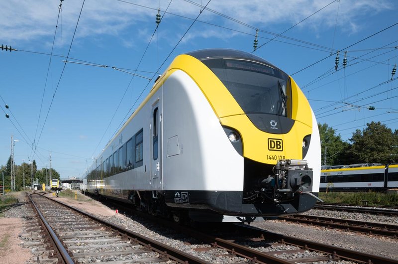 Ein weiß-gelber Regionalzug im bwegt-Design steht auf einem Bahngleis.