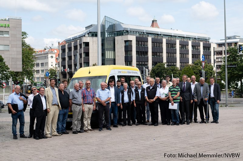 Eine Gruppe von dreißig Männern steht halbkreisförmig vor einem Bus