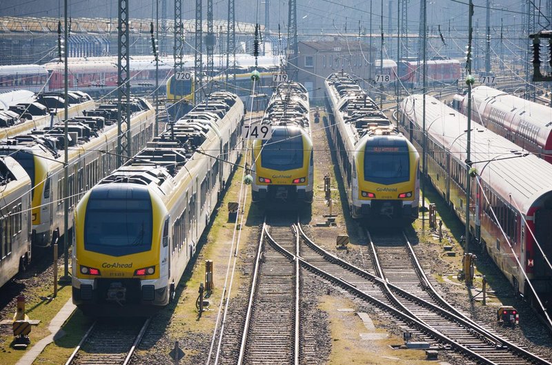 Drei gelb-weiße Züge im bwegt-Design stehen auf Gleisen am Stuttgarter Hauptbahnhof.